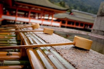 Wooden ladles on the edge of a water-filled basin in front of a Shinto shrine