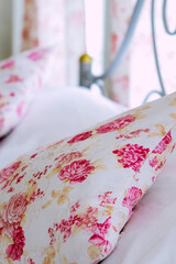 Bright bedroom interior with flower pattern pillows on bed 