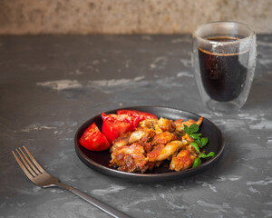Breakfast with a snack plate with fried chicken meat on a dark plate, basil leaves and strong black coffee