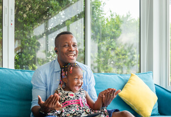 Cheerful african american father and daughter playing in living room, Happiness family concepts