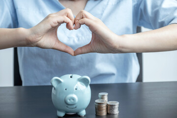 Woman hands making heart shape over blue piggy bank, step up start up business to success, Saving money for future plan and retirement fund concept