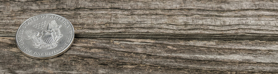 Banner / Web: Silbermünze (1 Oz American Silver Eagle) auf einem alten Holz-Hintergrund