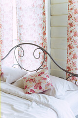 Bright bedroom interior with flower pattern pillows on bed 