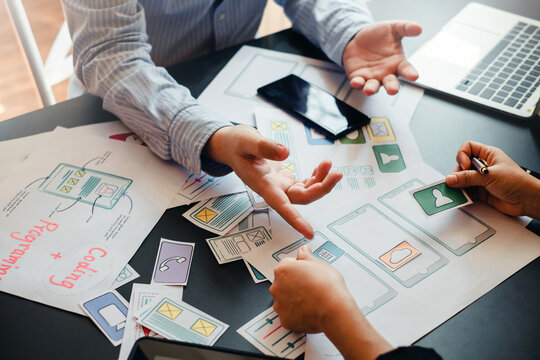 UI UX Graphic designer. Group of designer creativity drawing a website outline and website ux app development on mobile phone.