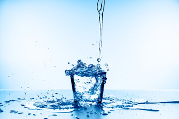 water splashing from glass isolated on blue background