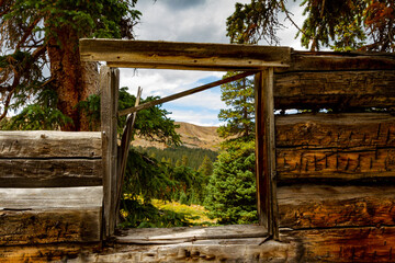 Broken down log cabin window over looking Rocky Mountains