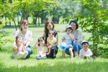 Fototapeta premium 緑あふれる公園で遊ぶ家族たちの集合写真