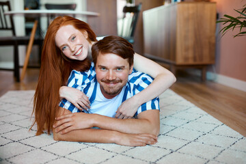 lovely couple lie on the floor in living room indoors, stay home during quarantine time, in love....