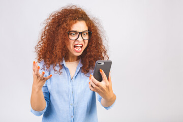 Angry young curly woman talking on the phone isolated on a white background. Image of screaming agressive young woman.