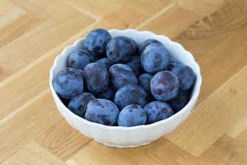 delicious fresh organic plums in a white bowl