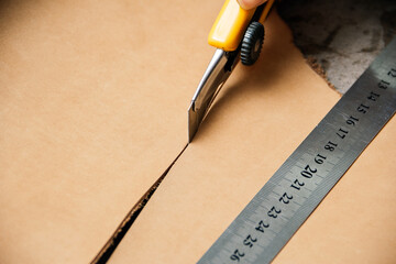 top view of cutting tool and metal ruler while producing leather goods at table