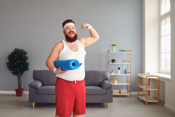 Funny fat man in sportswear shows muscles standing in the room at home