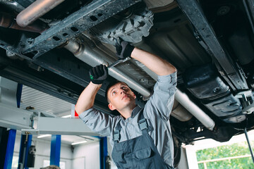 Portrait of a mechanic repairing a lifted car.