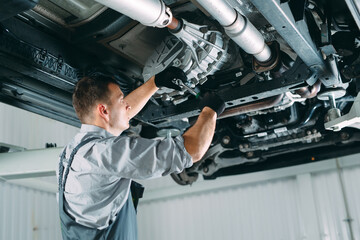 Portrait of a mechanic repairing a lifted car.