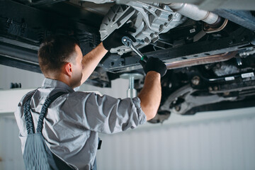 Portrait of a mechanic repairing a lifted car.