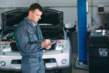 mechanic maintaining car record on clipboard at the repair shop.