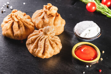 Appetizing traditional fried dumplings on a dark background among spices and sauces. Traditional food concept
