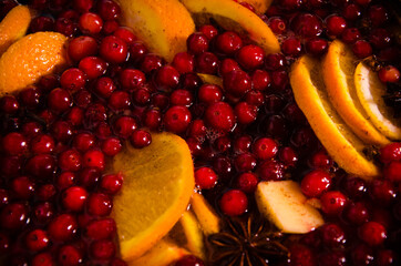 metal pot on the stove. Oranges and cranberries in mulled wine