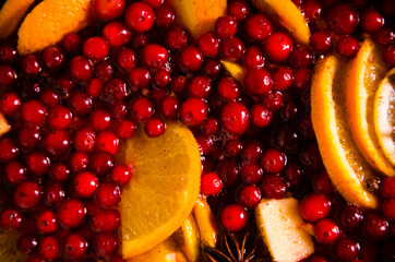 metal pot on the stove. Oranges and cranberries in mulled wine