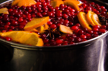 metal pot on the stove. Oranges and cranberries in mulled wine