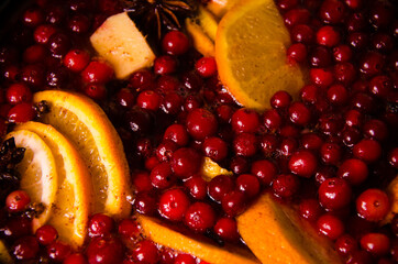 metal pot on the stove. Oranges and cranberries in mulled wine
