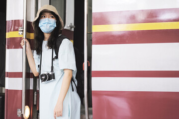 Asian travelers girl take a picture in train station with medical face mask to protection the Covid-19, new normal lifestyle