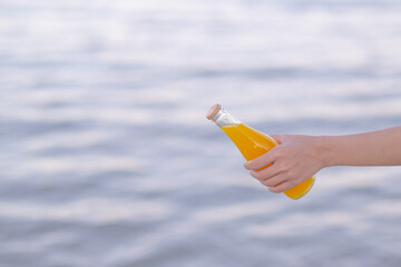 Girl and orange juice bottle on the beach, summer background concept