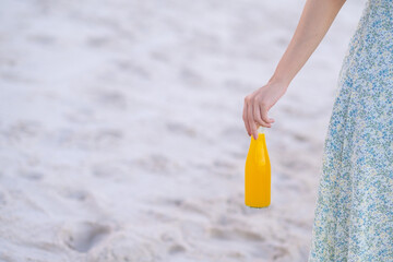 Girl and orange juice bottle on the beach, summer background concept