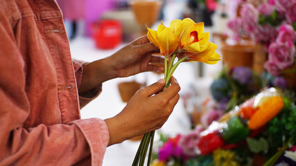 Woman’s hand holding daffodil yellow flowers, flourish store with blurred
