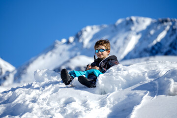 Fototapeta na wymiar Young Boy Sitting On The Snow Mountain. Winter time