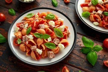 Conchiglie Tuna pasta with tomato sauce, feta cheese and basil on wooden table. healthy food