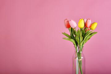Tulip flowers bouquet for celebration on pink background. Artificial tulips arrangement in vase.