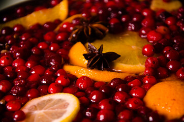 metal pot on the stove. Oranges and cranberries in mulled wine