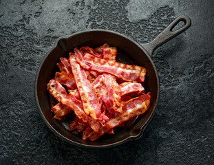 Fried crunchy Streaky Bacon pieces in a cast iron skillet