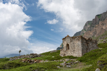 Fototapeta na wymiar Ruins of abandoned stone house in the mountainside against the cloudy sky. Eltyubyu, Kabardino-Balkaria, Russia