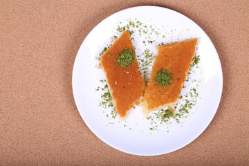 A slice piece of kunafa ramadan Arabic sweet pastries & dessert with creamy cheese & pistachios in the dish