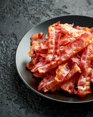 Fried crunchy Streaky Bacon pieces in a black plate