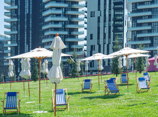 public park between skyscapers set up for the summer season with deck chairs and umbrellas