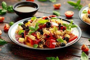 Antipasto salad with pasta, tomato, olives, red onion, bell pepper, salami, cheese, artichoke and basil.