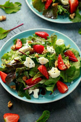 Goats cheese and strawberry summer salad served with nigella and sesame seeds drizzled with runny honey