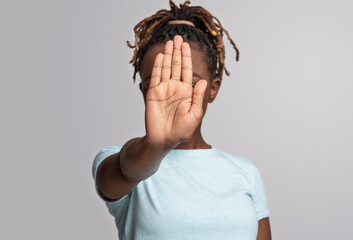 Black woman covering her face with palm, showing stop gesture