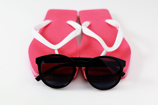 Pink flip flop and sunglasses isolated on white background