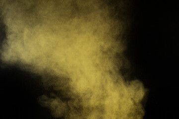 Yellow powder explosion on black background. Colored powder cloud. Colorful dust explode. Paint  Holi.