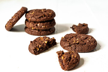 Stuck of Homemade american chocolate cookies with nuts on white wooden background. Fresh pastry.