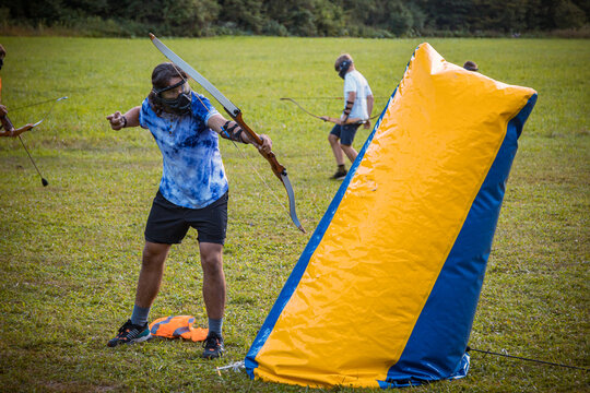 Teenage boy playing archery tag on a meadow