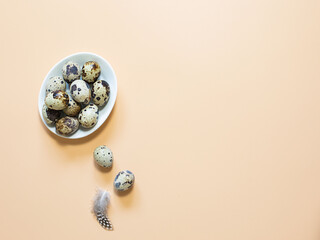 Quail eggs in a bowl on a yellow-pink background with copy space.
