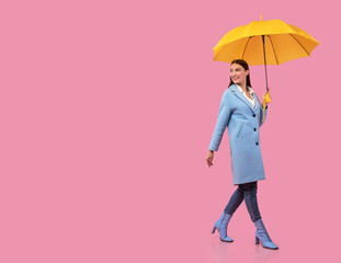 Portrait of excited young woman walking with yellow parasol