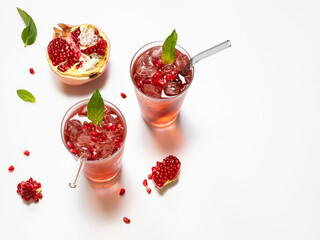 Pomegranate juice on a white background in glass glasses with glass straws.