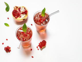 Pomegranate juice on a white background in glass glasses with glass straws.