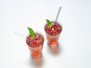 Pomegranate juice on a white background in a glass glasses with glass straws.